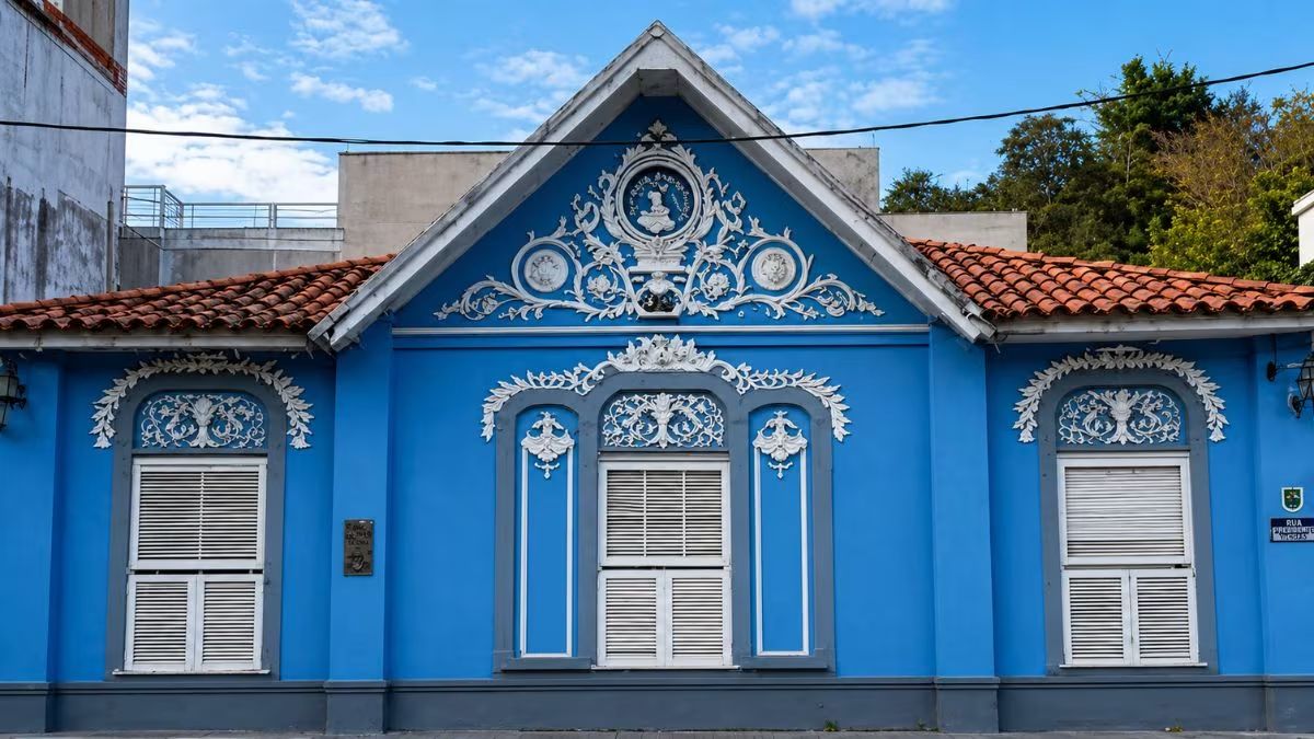 Fachada azul da Casa da Princesa Isabel em Barra do Piraí destacando ornamentos brancos em estuque guirlandas em alto relevo e medalhão imperial no frontão triangular.