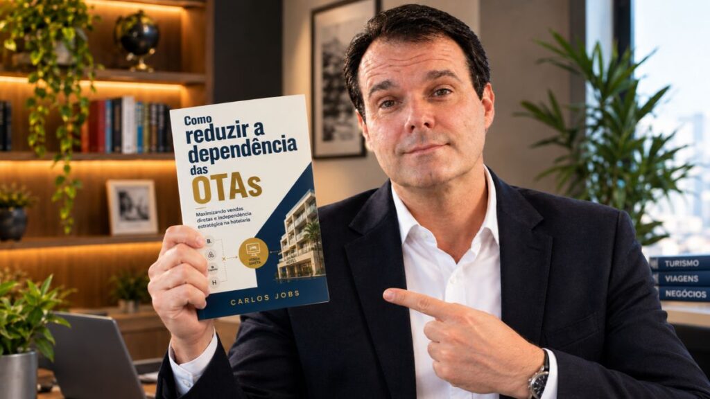 Carlos Jobs vestindo blazer escuro e camisa branca, segurando e apontando para a capa do livro Como Reduzir a Dependência das OTAs.